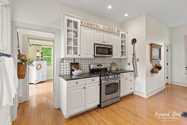 217 N Maple St, Momence, IL 60954 - kitchen featuring stainless steel appliances, dark countertops, light wood-style floors, tasteful backsplash, and white cabinets
