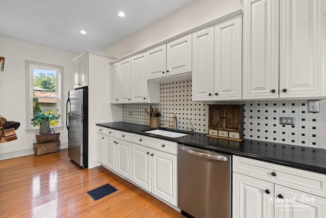 217 N Maple St, Momence, IL 60954 - kitchen featuring appliances with stainless steel finishes, white cabinetry, backsplash, dark countertops, and light wood-type flooring