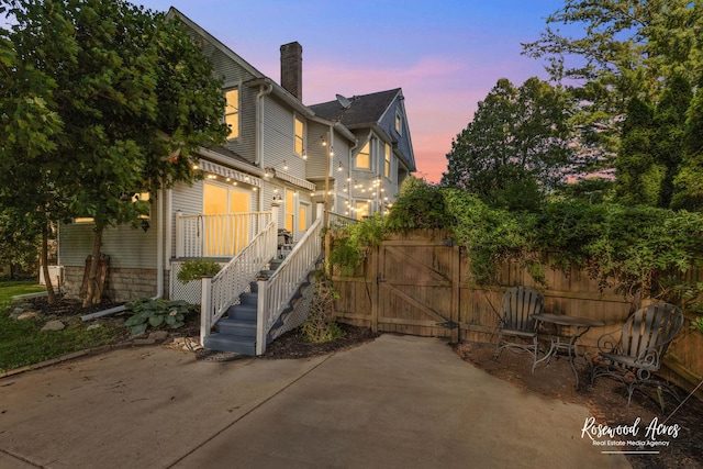 217 N Maple St, Momence, IL 60954 - back of house at dusk featuring a chimney, a patio, and a gate