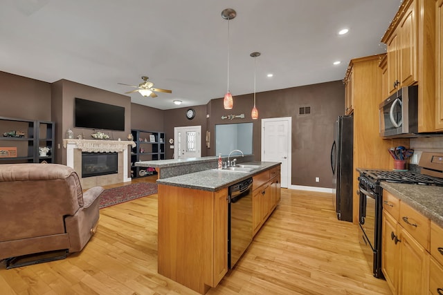 300 Village Ln, Seneca, IL 61360 - kitchen with black appliances, a center island with sink, ceiling fan, light wood-type flooring, and a glass covered fireplace