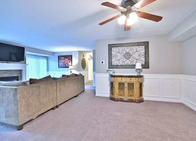 14031 Norwich Ln Unit 101, Orland Park, IL 60467 - living area featuring carpet, a stone fireplace, wainscoting, a ceiling fan, and a decorative wall