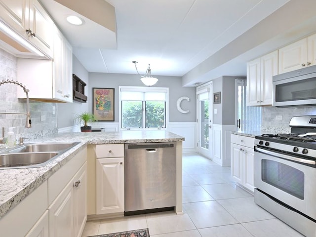 14031 Norwich Ln Unit 101, Orland Park, IL 60467 - kitchen featuring appliances with stainless steel finishes, a peninsula, decorative backsplash, white cabinets, and a wainscoted wall