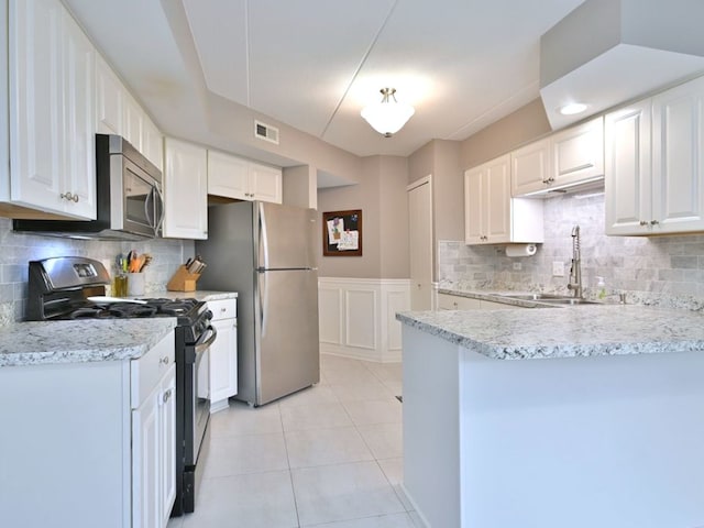 14031 Norwich Ln Unit 101, Orland Park, IL 60467 - kitchen featuring appliances with stainless steel finishes, white cabinetry, a peninsula, light tile patterned floors, and wainscoting