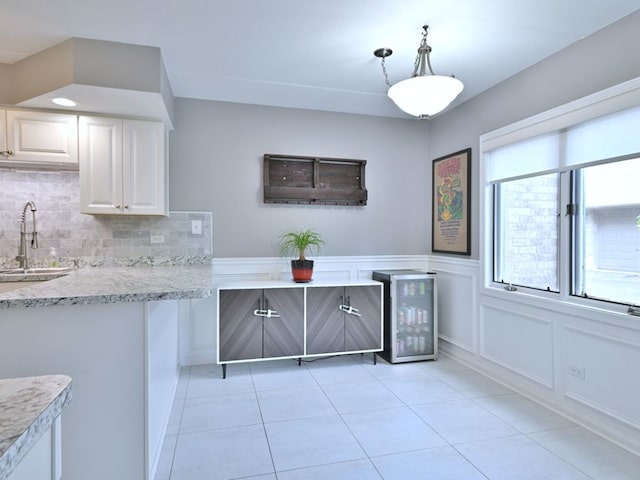 14031 Norwich Ln Unit 101, Orland Park, IL 60467 - kitchen with light tile patterned floors, decorative backsplash, beverage cooler, white cabinets, and decorative light fixtures