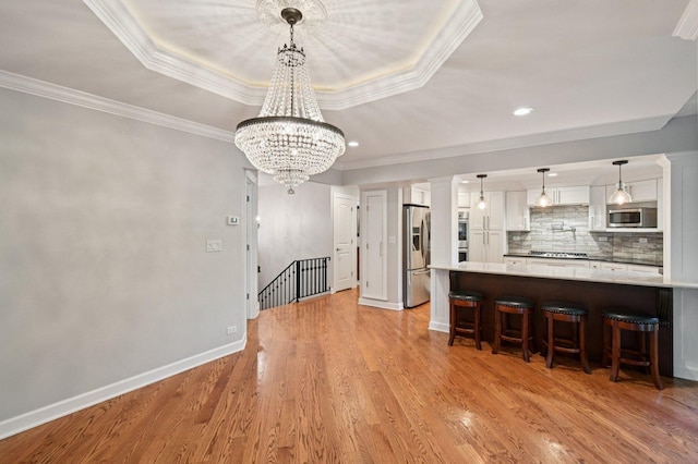 129 Kainer Ave, Barrington, IL 60010 - kitchen with stainless steel appliances, white cabinets, a tray ceiling, a kitchen bar, and ornamental molding