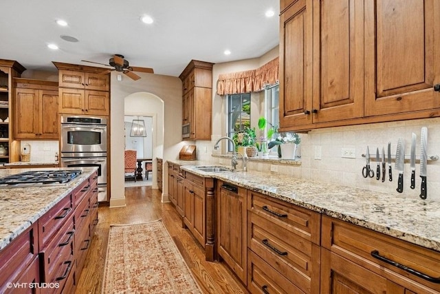 41W590 Bowgren Dr, Campton Hills, IL 60119 - kitchen featuring appliances with stainless steel finishes, light wood-style floors, a ceiling fan, arched walkways, and light stone countertops