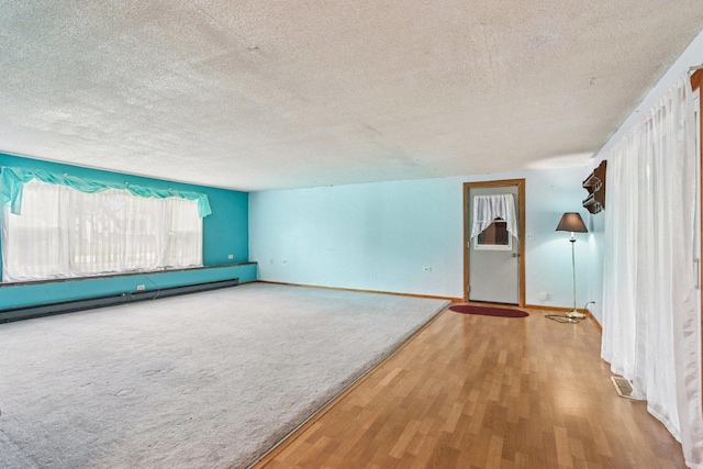 602 Daisy Ln, Round Lake Beach, IL 60073 - unfurnished room with a textured ceiling, baseboard heating, and wood finished floors