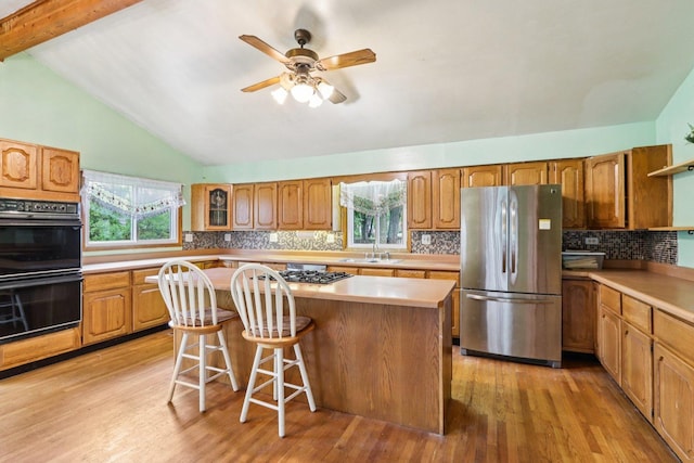 602 Daisy Ln, Round Lake Beach, IL 60073 - kitchen with appliances with stainless steel finishes, a center island, light wood-style floors, a kitchen bar, and lofted ceiling