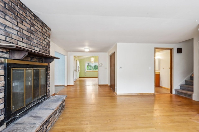 602 Daisy Ln, Round Lake Beach, IL 60073 - unfurnished living room featuring a brick fireplace, light wood-style floors, and stairs
