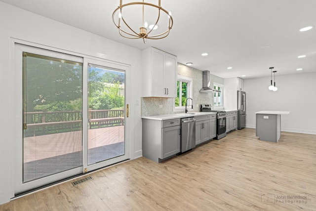 154 Newton Ave, Glen Ellyn, IL 60137 - kitchen with appliances with stainless steel finishes, gray cabinetry, wall chimney exhaust hood, light wood finished floors, and light countertops
