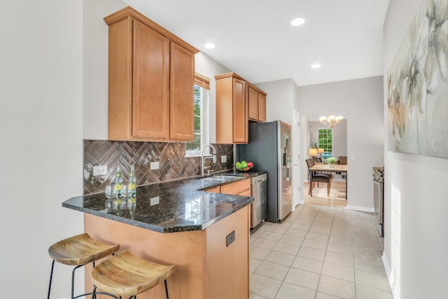 6406 Cunningham Ct, Gurnee, IL 60031 - kitchen featuring appliances with stainless steel finishes, a peninsula, tasteful backsplash, a chandelier, and light tile patterned floors