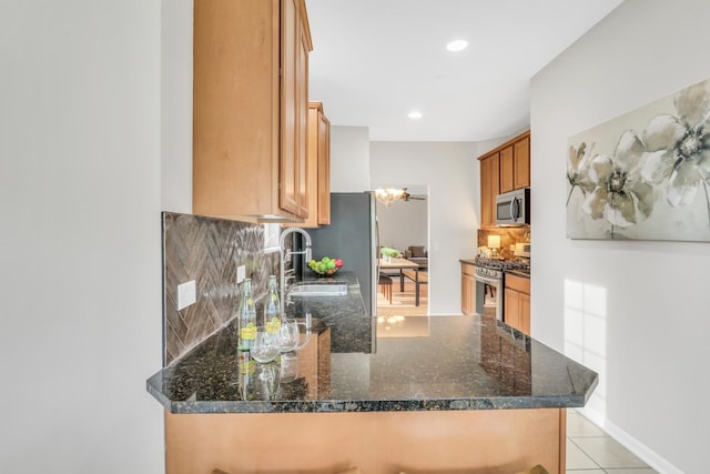 6406 Cunningham Ct, Gurnee, IL 60031 - kitchen with stainless steel appliances, a peninsula, backsplash, dark stone counters, and light tile patterned floors