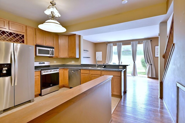 2224 Flagstone Ln Unit 2224, Carpentersville, IL 60110 - kitchen with stainless steel appliances, a peninsula, dark countertops, light wood-style floors, and hanging light fixtures