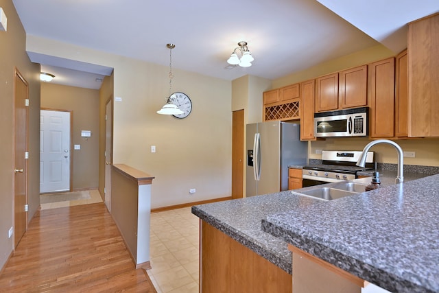 2224 Flagstone Ln Unit 2224, Carpentersville, IL 60110 - kitchen with appliances with stainless steel finishes, dark countertops, decorative light fixtures, brown cabinetry, and light wood-type flooring