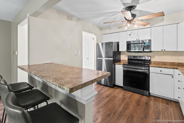 7526 S Cork Ave Unit 7526, Justice, IL 60458 - kitchen featuring appliances with stainless steel finishes, a kitchen breakfast bar, a ceiling fan, tasteful backsplash, and dark wood-style flooring