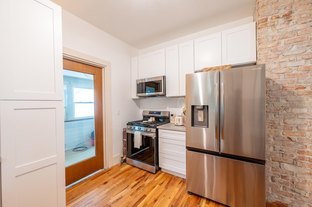 102 E Front St, Mount Morris, IL 61054 - kitchen featuring appliances with stainless steel finishes, white cabinets, light wood-style flooring, and light countertops