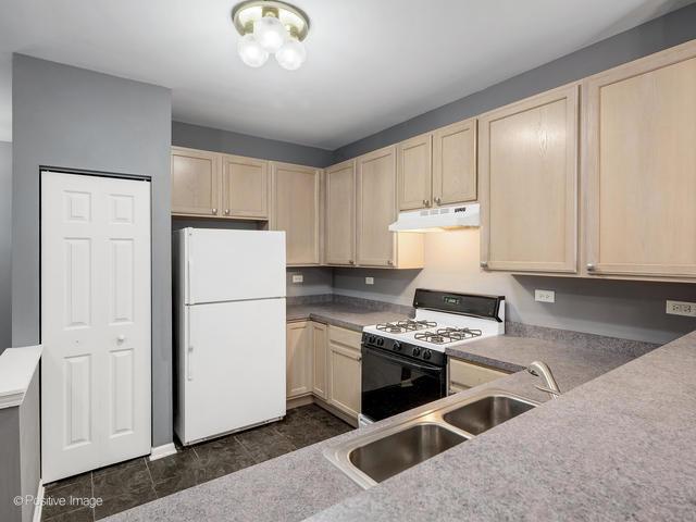 835 Genesee Dr, Naperville, IL 60563 - kitchen with white appliances, under cabinet range hood, light brown cabinetry, and light countertops