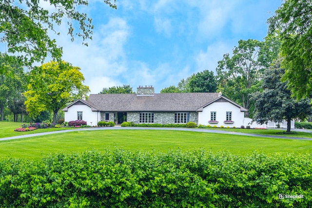 ranch-style house with stone siding, a chimney, and a front lawn
