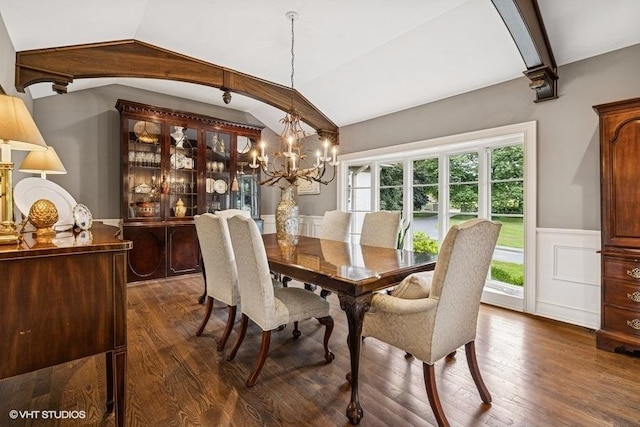 dining space featuring lofted ceiling, wainscoting, dark wood-style flooring, a chandelier, and a decorative wall