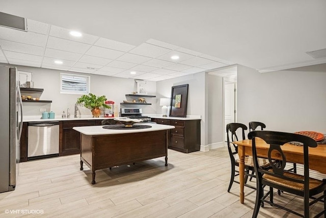 kitchen with appliances with stainless steel finishes, dark brown cabinetry, wall chimney exhaust hood, open shelves, and recessed lighting