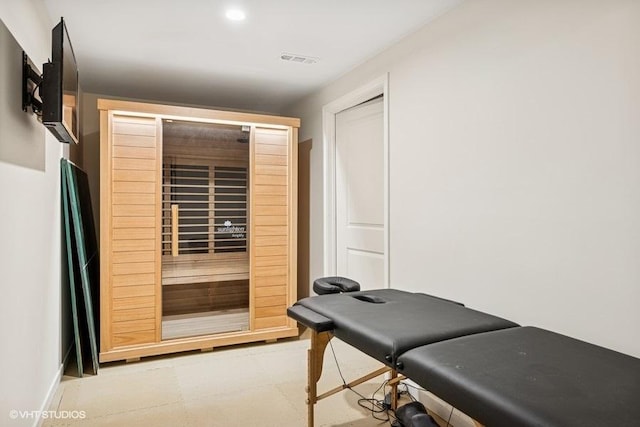 exercise room with light floors and a sauna / steam room