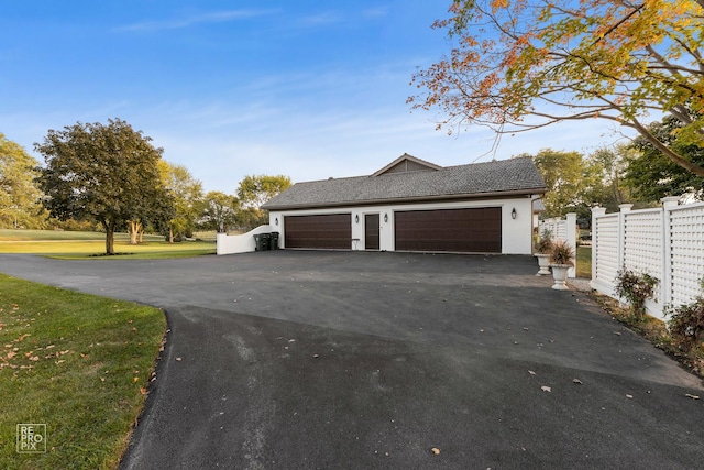 view of side of home featuring driveway, an attached garage, and stucco siding