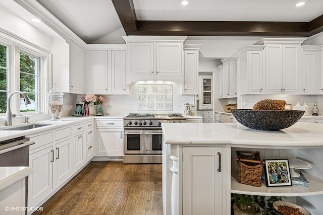 kitchen with double oven range, white cabinets, light countertops, decorative backsplash, and dark wood-type flooring