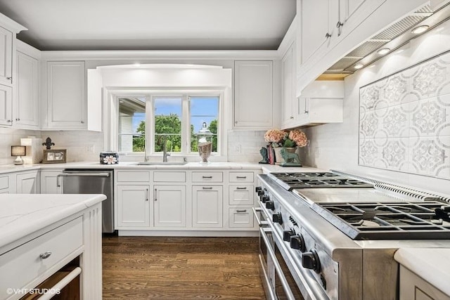 kitchen featuring appliances with stainless steel finishes, under cabinet range hood, white cabinetry, dark wood-style floors, and tasteful backsplash
