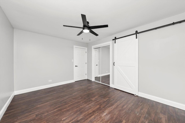 230 Mantua St, Park Forest, IL 60466 - unfurnished bedroom featuring dark wood-style floors, a barn door, ceiling fan, and a closet