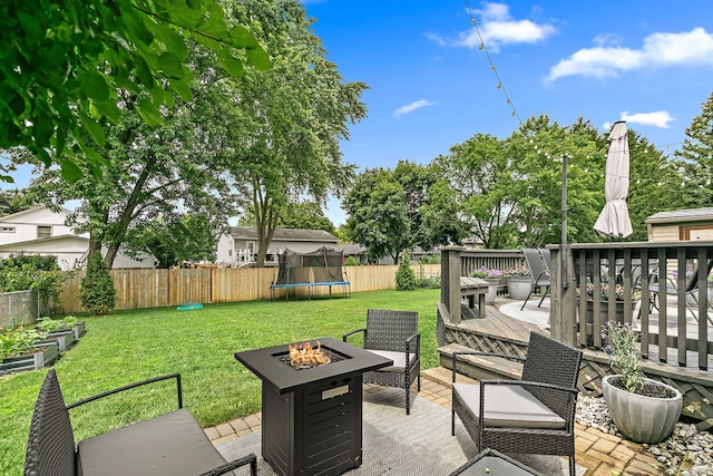 588 Arthur Dr, Cary, IL 60013 - fenced backyard featuring a fire pit, a deck, a trampoline, and a garden