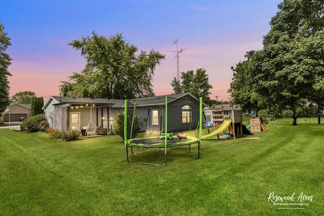 601 E Washington St, Ashkum, IL 60911 - back of property at dusk featuring a trampoline, a playground, and a yard