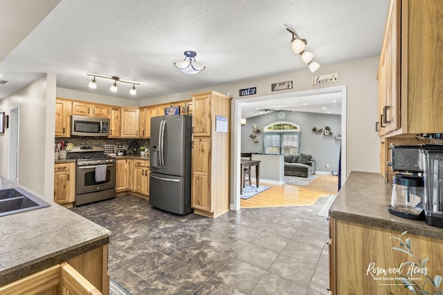 601 E Washington St, Ashkum, IL 60911 - kitchen featuring appliances with stainless steel finishes, rail lighting, a textured ceiling, backsplash, and open floor plan
