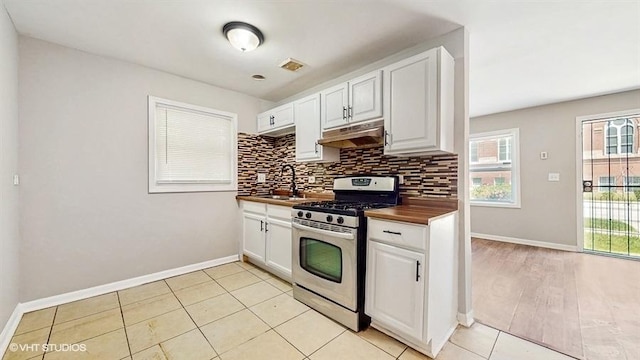 309 W 109th Pl, Chicago, IL 60628 - kitchen featuring stainless steel gas range oven, under cabinet range hood, tasteful backsplash, white cabinetry, and butcher block counters