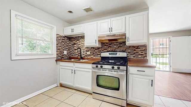 309 W 109th Pl, Chicago, IL 60628 - kitchen featuring under cabinet range hood, gas stove, wood counters, light tile patterned floors, and decorative backsplash
