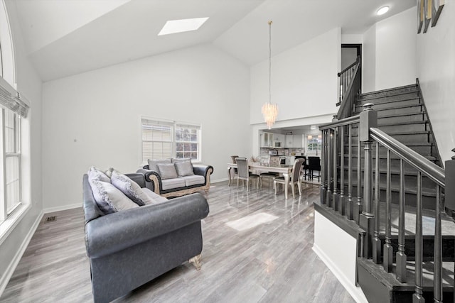 3032 Sandy Ridge Dr, Steger, IL 60475 - living room featuring stairway, a skylight, high vaulted ceiling, wood finished floors, and a chandelier