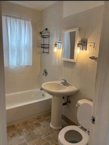 3608 Jackson St Unit 2E, Bellwood, IL 60104 - bathroom with washtub / shower combination, tile walls, and stone finish flooring