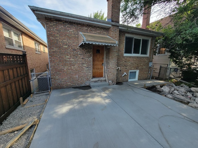 6308 W Cornelia Ave, Chicago, IL 60634 - rear view of house with brick siding, a chimney, a gate, and a patio