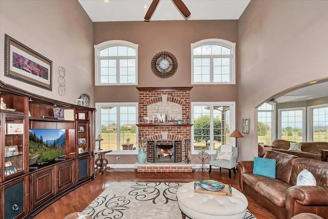 24155 S Blackhawk Ln, Manhattan, IL 60442 - living area with ceiling fan, wood finished floors, a high ceiling, arched walkways, and a brick fireplace