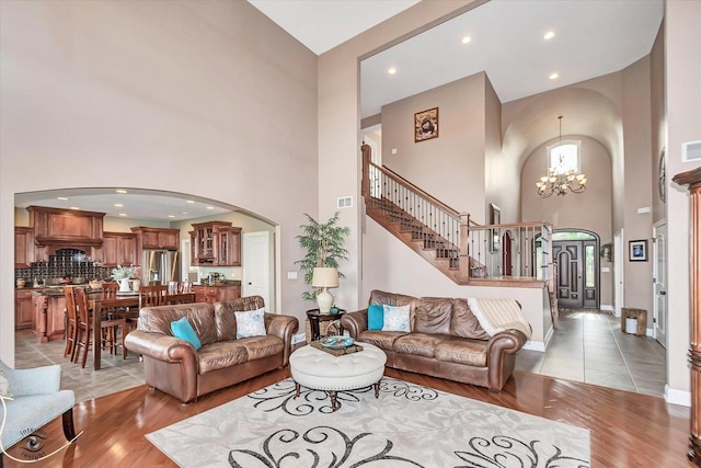 24155 S Blackhawk Ln, Manhattan, IL 60442 - living room with a towering ceiling, arched walkways, a chandelier, light wood-style floors, and stairs