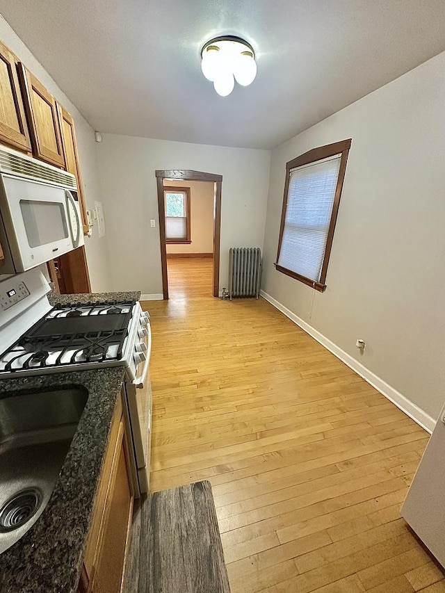 3514 N Lawndale Ave Unit 2, Chicago, IL 60618 - kitchen featuring white microwave, radiator heating unit, gas stove, brown cabinetry, and light wood finished floors