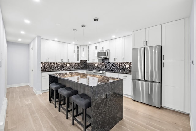 974 Crabapple Dr Unit 308, Prospect Heights, IL 60070 - kitchen featuring appliances with stainless steel finishes, light wood finished floors, backsplash, a breakfast bar area, and a kitchen island