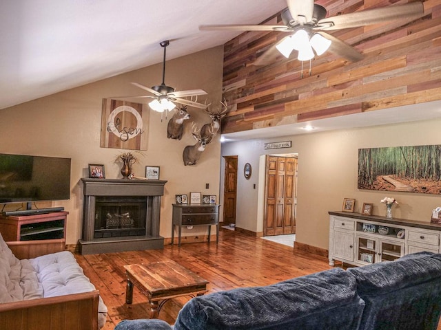 26 N Deer Lk, Villa Grove, IL 61956 - living room featuring ceiling fan, a fireplace with raised hearth, wood finished floors, high vaulted ceiling, and wooden walls