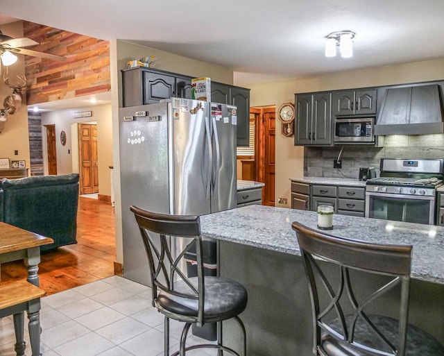 26 N Deer Lk, Villa Grove, IL 61956 - kitchen with stainless steel appliances, custom range hood, a ceiling fan, a kitchen breakfast bar, and light stone countertops