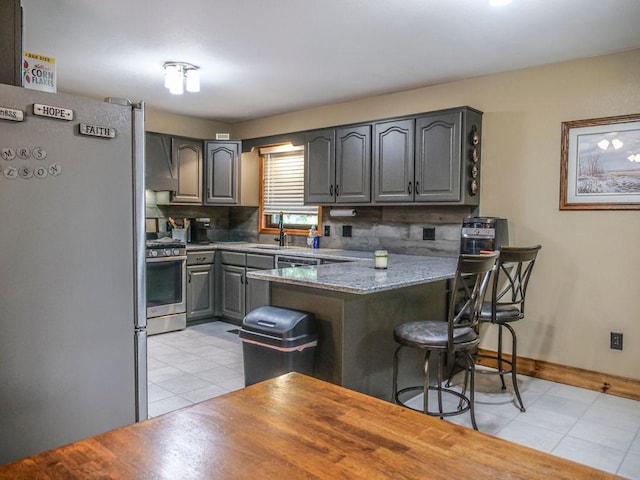 26 N Deer Lk, Villa Grove, IL 61956 - kitchen with stainless steel appliances, gray cabinetry, light tile patterned flooring, and a peninsula