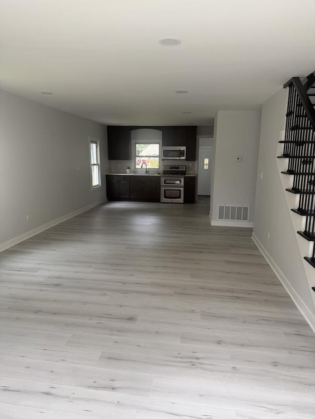 309 SE Circle Dr, Joliet, IL 60433 - unfurnished living room featuring stairway and light wood-style floors