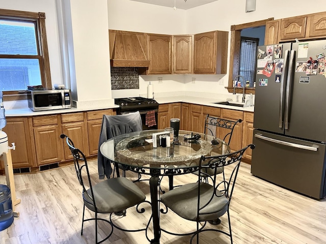 2603 3rd St, Peru, IL 61354 - kitchen featuring stainless steel appliances, premium range hood, light wood-type flooring, brown cabinets, and light countertops