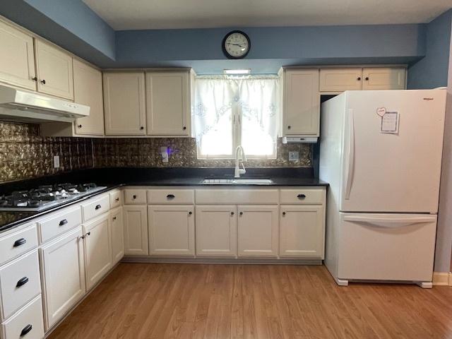 512 Tana Ln, Joliet, IL 60435 - kitchen featuring freestanding refrigerator, stainless steel gas cooktop, under cabinet range hood, dark countertops, and light wood finished floors