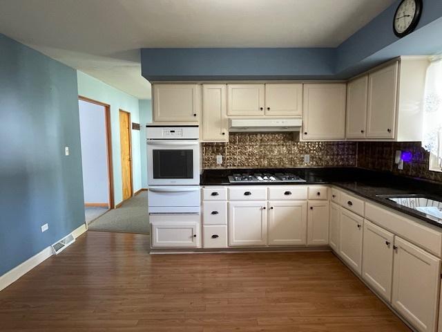 512 Tana Ln, Joliet, IL 60435 - kitchen featuring white oven, a warming drawer, dark countertops, under cabinet range hood, and backsplash