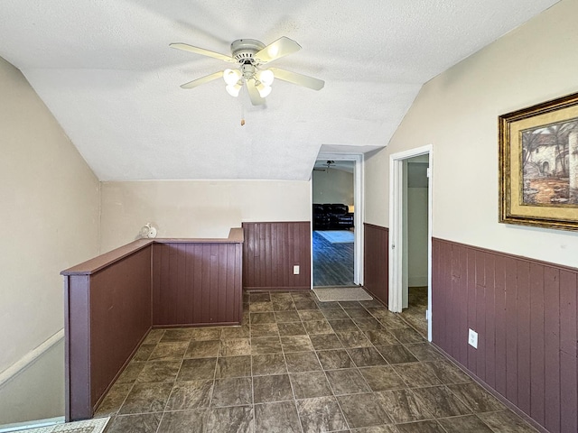 725 Opal St, Marseilles, IL 61341 - hallway with vaulted ceiling, a wainscoted wall, a textured ceiling, wood walls, and dark stone finish floors