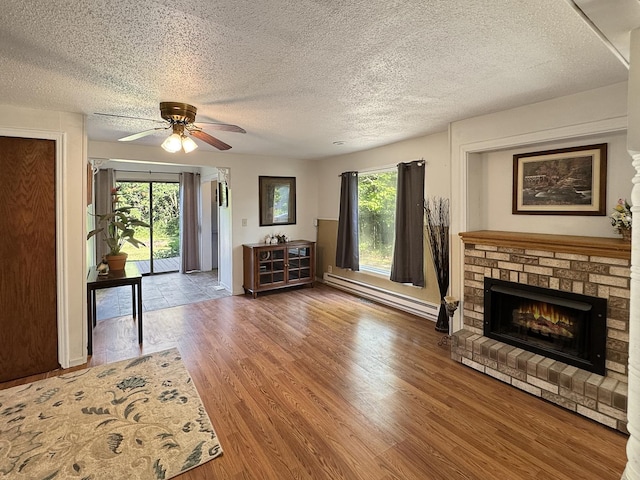 725 Opal St, Marseilles, IL 61341 - unfurnished living room featuring a textured ceiling, wood finished floors, ceiling fan, a fireplace, and baseboard heating